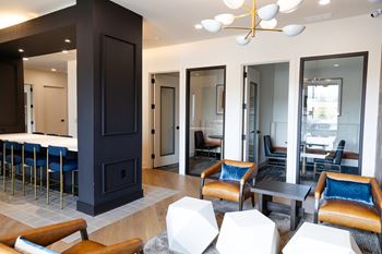A modern living room with a dark wood fireplace and blue chairs.